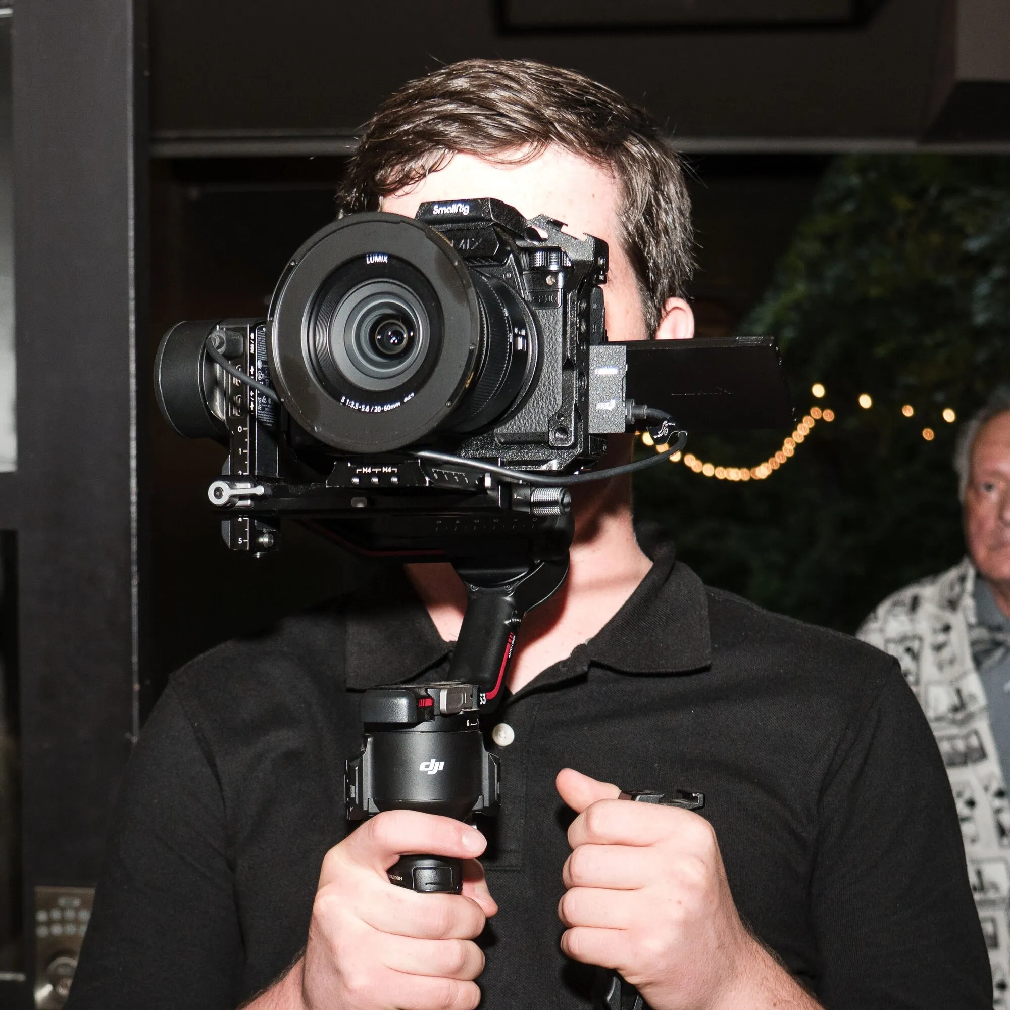 Mason behind a cinema camera on a gimbal, lens pointed at you