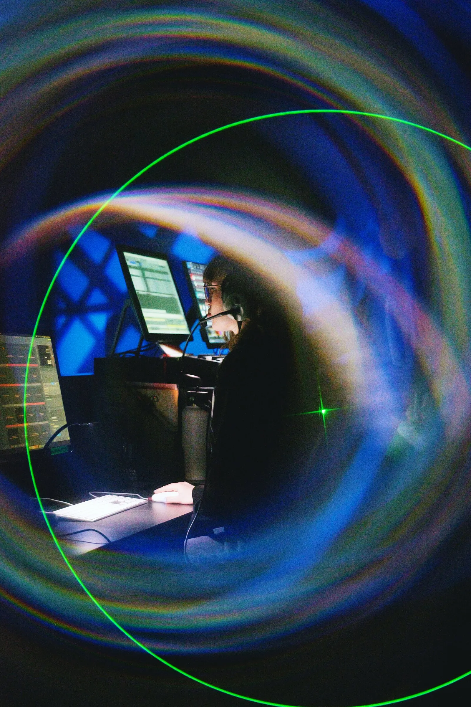A pianist on a dark stage seen through a ring of blue light
