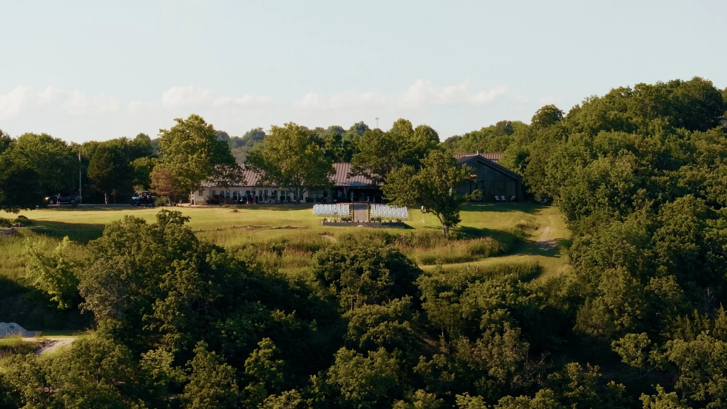Aerial view of a lakeside venue and lawn surrounded by trees
